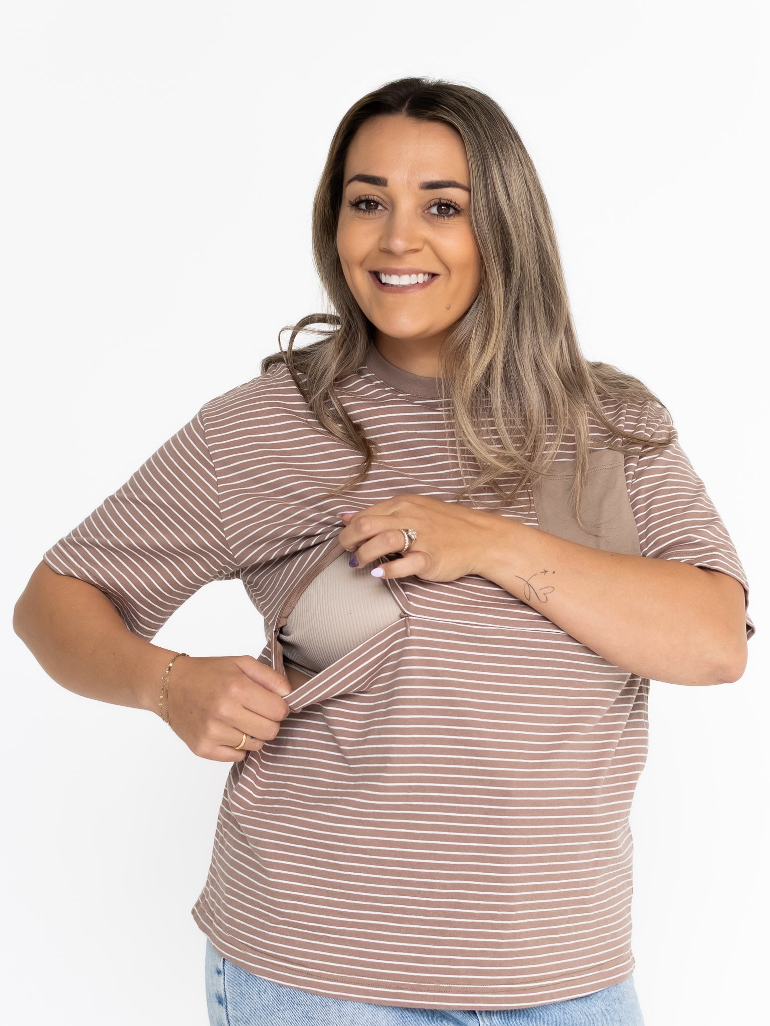 Smiling mum opening the two-way zip on the brown and white striped Mackenzie breastfeeding tee
