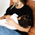 Mum feeding her baby in the black Indiana breastfeeding tee by Milky Threads Co, on a tan leather chair