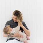 Mum sitting on a chair breastfeeding her baby in the black and white Mackenzie tee