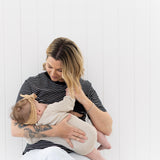 Mum sitting on a chair breastfeeding her baby in the black and white Mackenzie tee