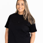 Front view of the Indiana breastfeeding tee in black, worn oversized with jeans