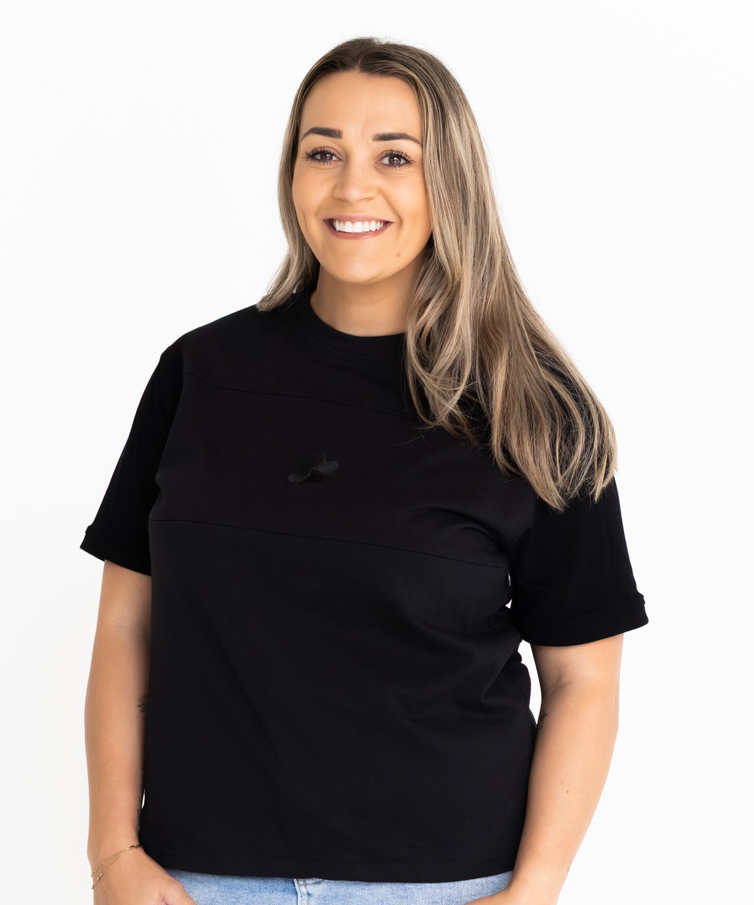 Front view of the Indiana breastfeeding tee in black, worn oversized with jeans