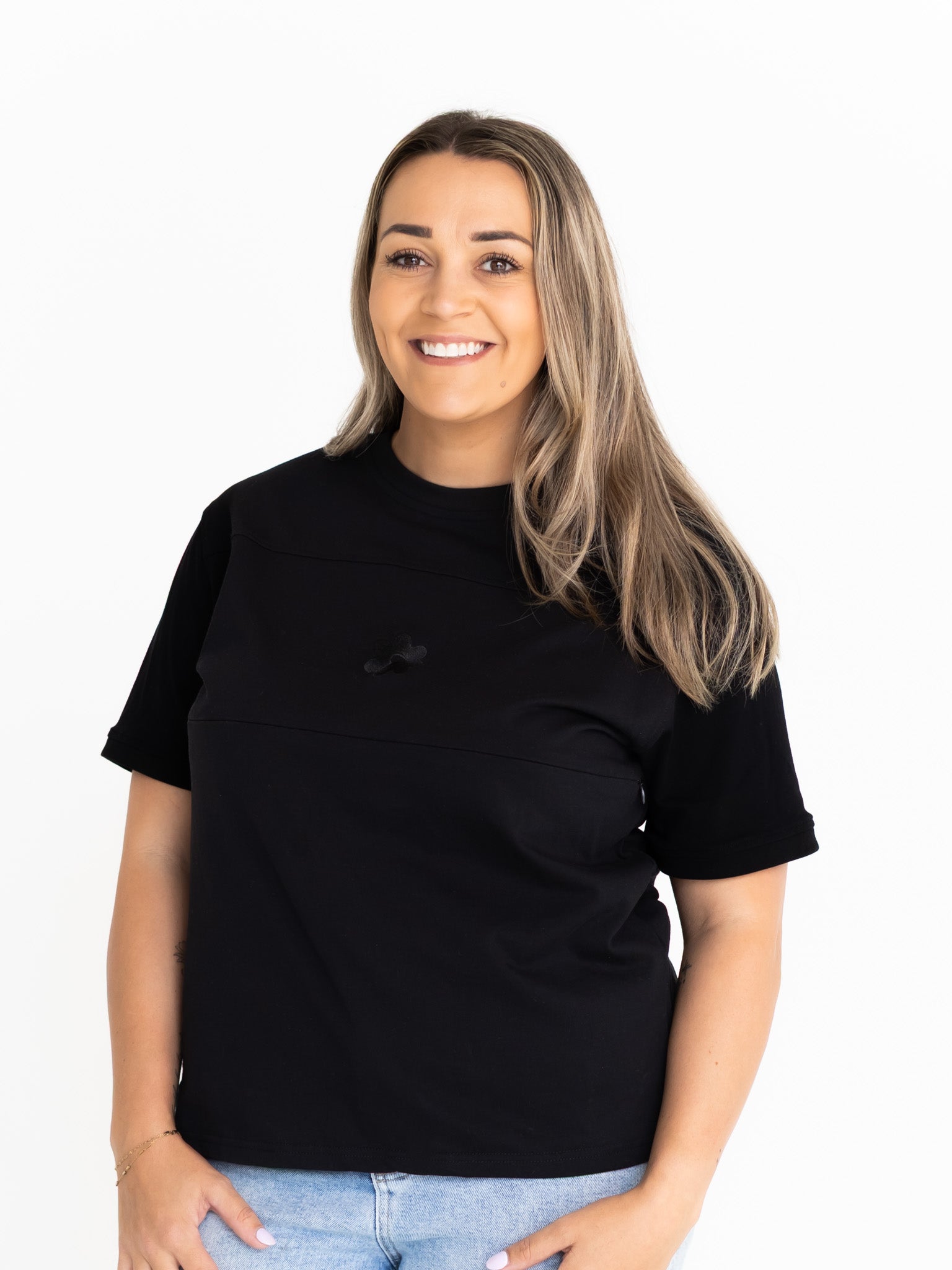 Front view of the Indiana breastfeeding tee in black, worn oversized with jeans