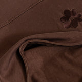 Close-up of the Milky Threads Co flower logo and panel and zip detail on the brown and pink Indiana tee