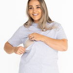 Smiling mum opening the discreet two-way zip on the light grey Indiana breastfeeding tee
