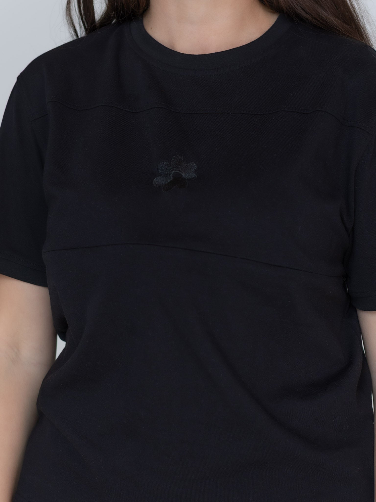 Close-up of the Milky Threads Co flower logo and panel detail on the black Indiana tee