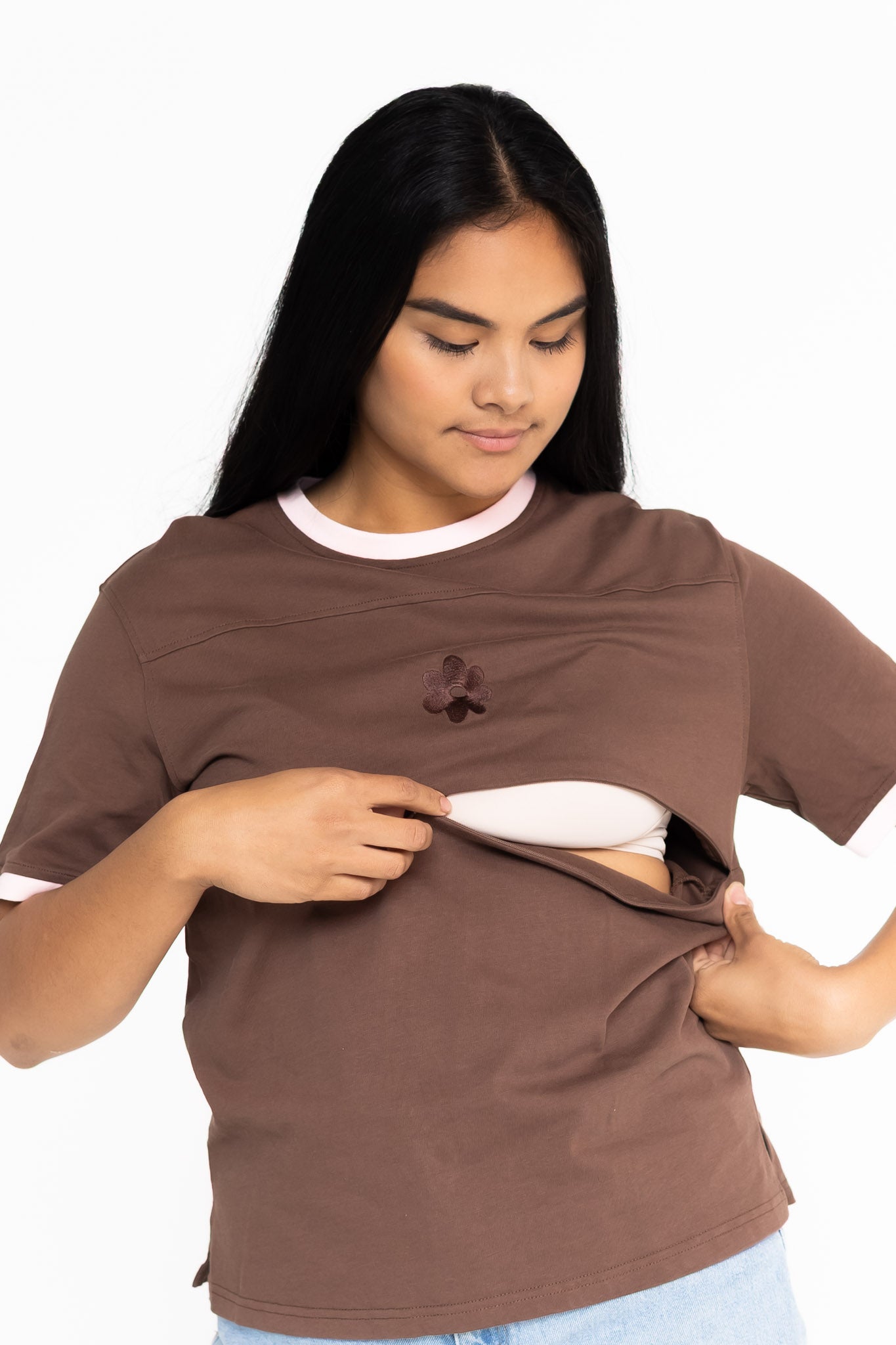 Mum opening the discreet two-way zip on the brown Indiana breastfeeding tee with pink trim