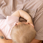 Overhead view of a baby breastfeeding in mum's brown and white striped Mackenzie tee