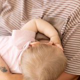 Overhead view of a baby breastfeeding in mum's brown and white striped Mackenzie tee